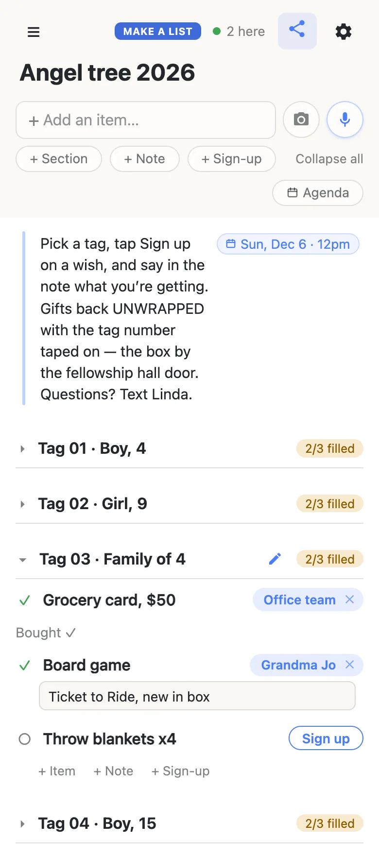 A donor’s phone showing the same Angel tree 2026 list, with “2 here” and a green dot in the header. Tags 01, 02 and 04 are folded with their counts. Tag 03 · Family of 4 is open and now reads 2/3 filled: the Office team has the Grocery card, $50 (“Bought ✓”), Grandma Jo has just signed up for the Board game and is typing “Ticket to Ride, new in box” into the note box beneath it, and Throw blankets x4 still shows a Sign up button.