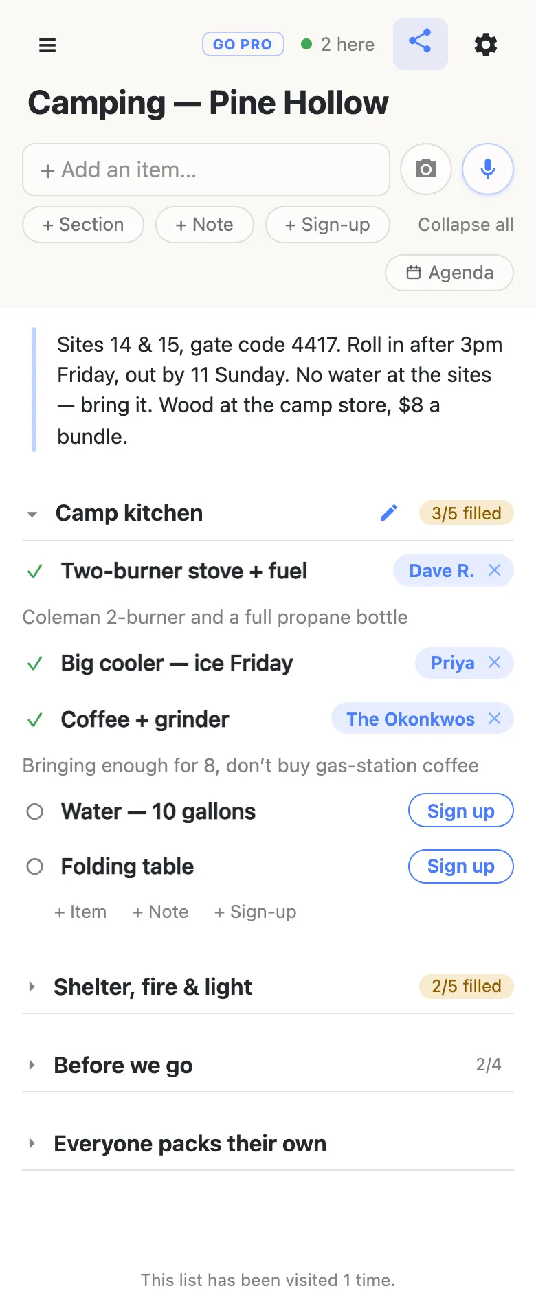 A phone showing a list titled “Camping — Pine Hollow”. A note at the top gives the site numbers, the gate code, arrival and departure times and the price of firewood. The Camp kitchen section reads 3/5 filled: a two-burner stove claimed by Dave R. with the note “Coleman 2-burner and a full propane bottle”, the big cooler claimed by Priya, coffee and grinder claimed by The Okonkwos, and water and a folding table still showing Sign up buttons.