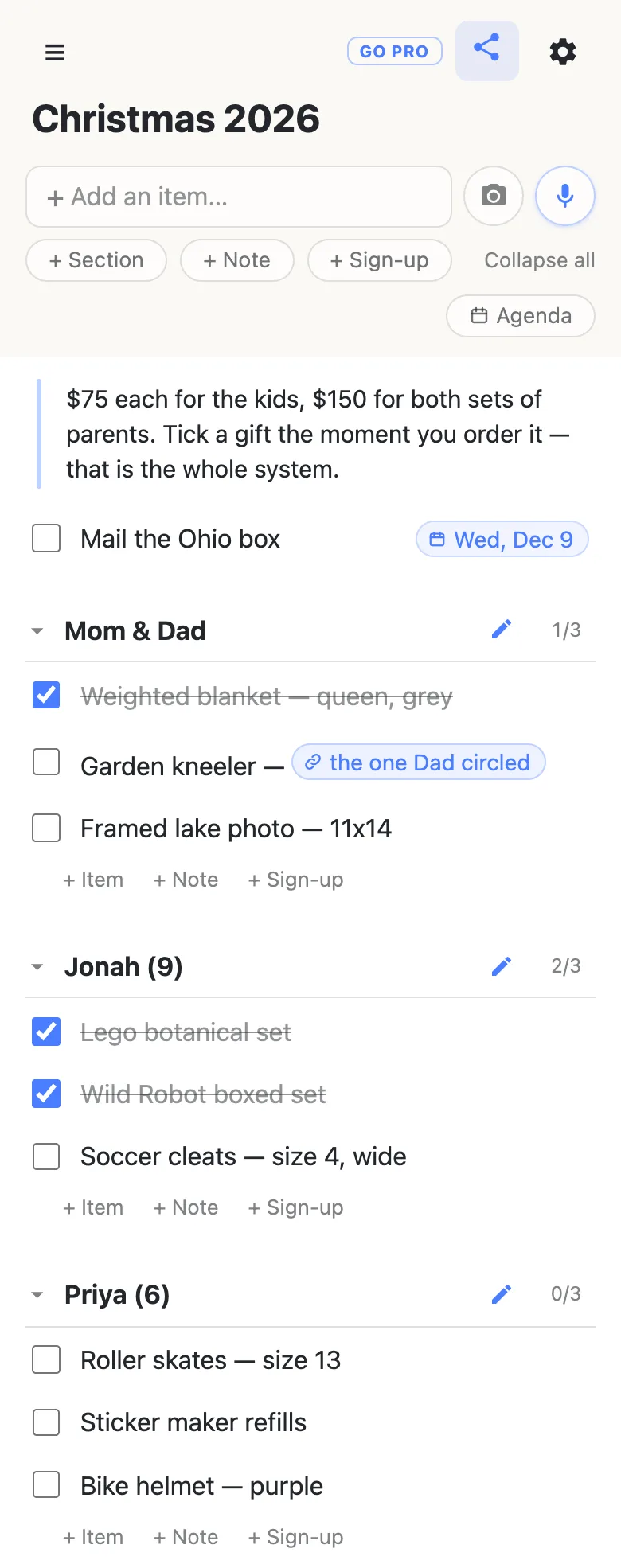 A shared list titled “Christmas 2026” on a phone. A note at the top reads “$75 each for the kids, $150 for both sets of parents. Tick a gift the moment you order it — that is the whole system.” Below it a dated row, Mail the Ohio box, carries a chip reading Wed, Dec 9. Three sections follow: Mom & Dad at 1/3 with Weighted blanket checked off and struck through, Garden kneeler carrying a link chip labelled “the one Dad circled”, and Framed lake photo; Jonah (9) at 2/3; Priya (6) at 0/3.