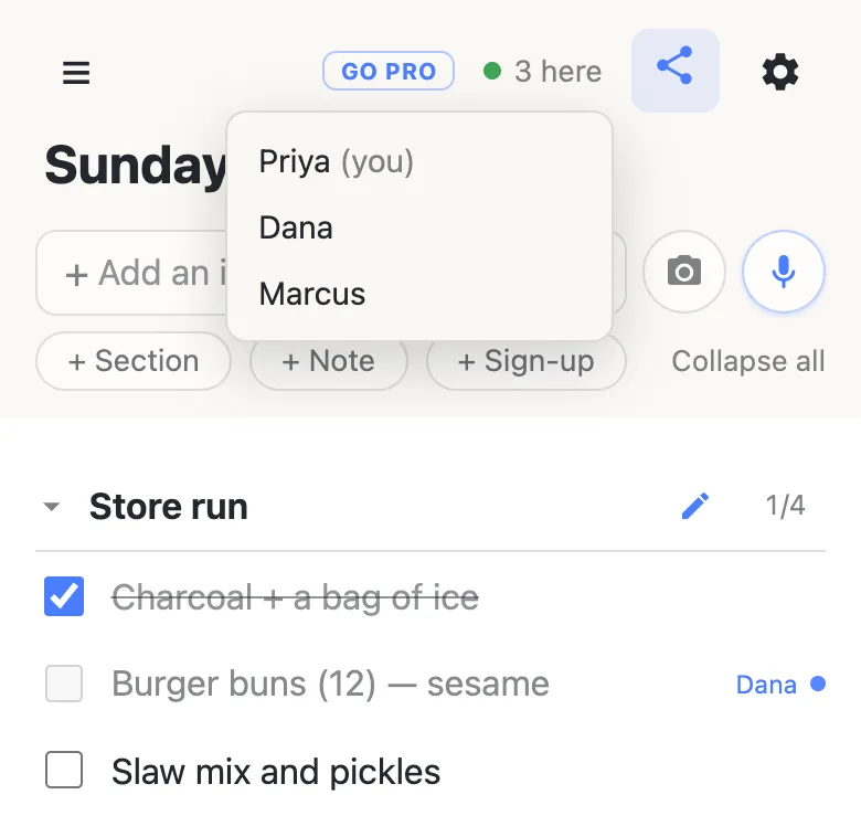 A shared cookout list on a phone: the header shows a green dot and “3 here”, with the tapped roster open listing Priya (you), Dana and Marcus. Below, the “Burger buns (12) — sesame” row is greyed with Dana’s name beside it.